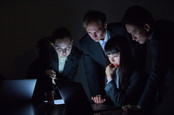 group of people in suits look at laptop screens